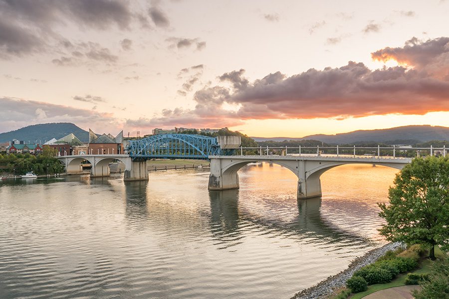 Chattanooga, TN - Long Distance View of Chattanooga, Tennessee City Skyline at Sunset Displaying a Large River and Bridge That Crosses it